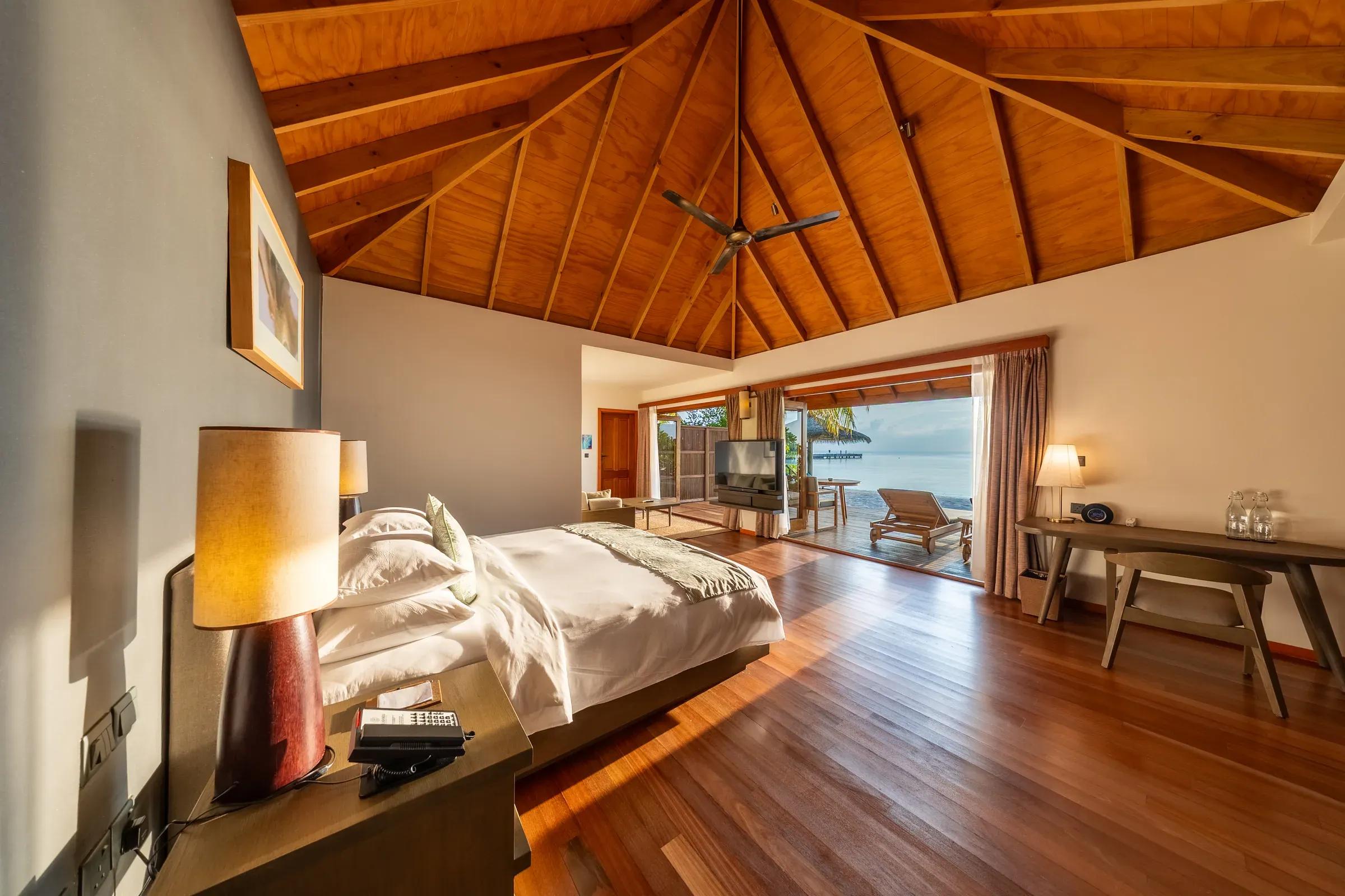 Interno della Sunset Jacuzzi Beach Villa con letto matrimoniale e vista sulla terrazza verso il mare al Veligandu Island Resort & Spa.