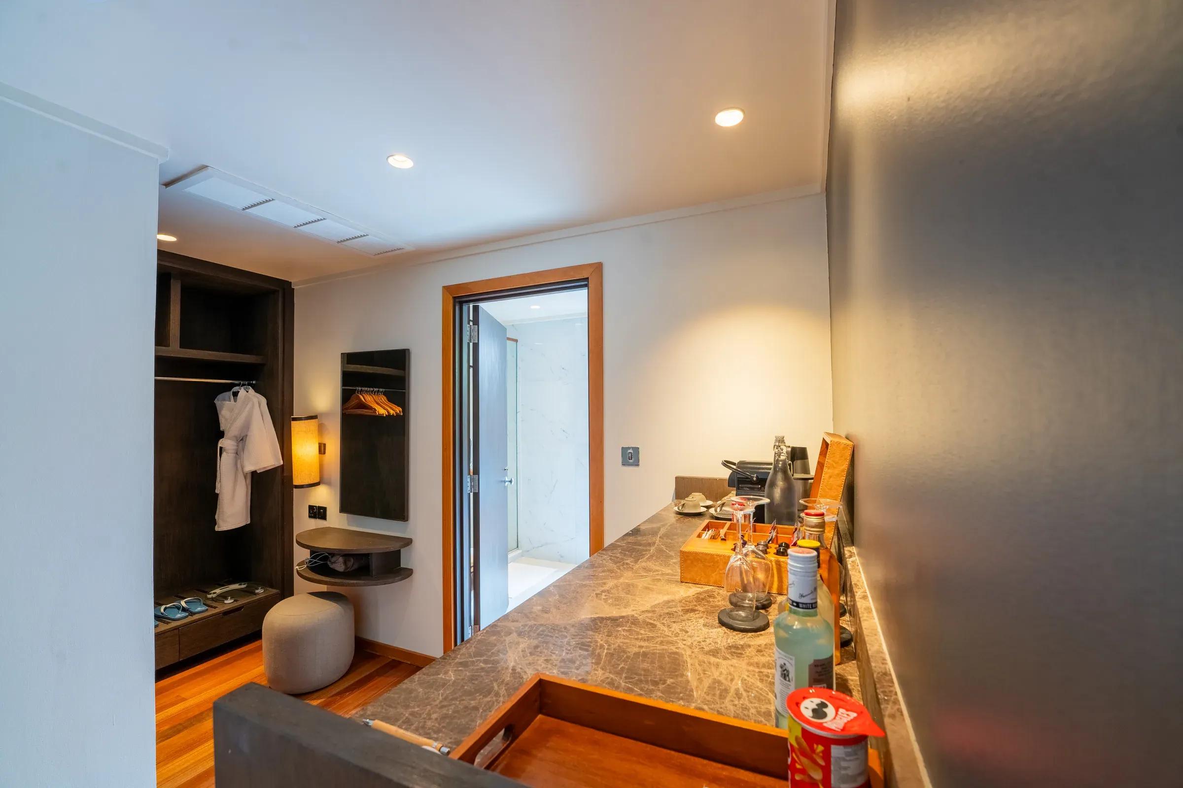 Interno della Sunset Jacuzzi Beach Villa con minibar e armadio aperto al Veligandu Island Resort & Spa.