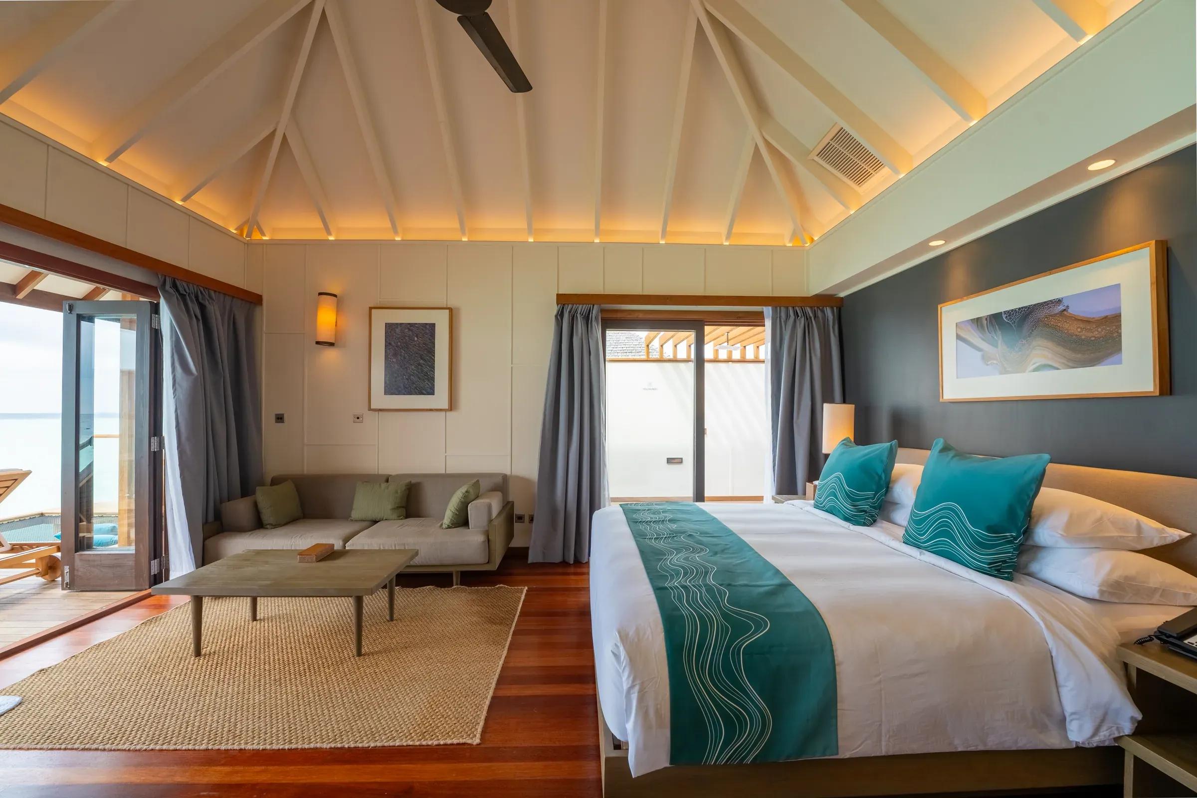 Interno della Sunset Ocean Villa con letto e area soggiorno presso il Veligandu Island Resort & Spa.