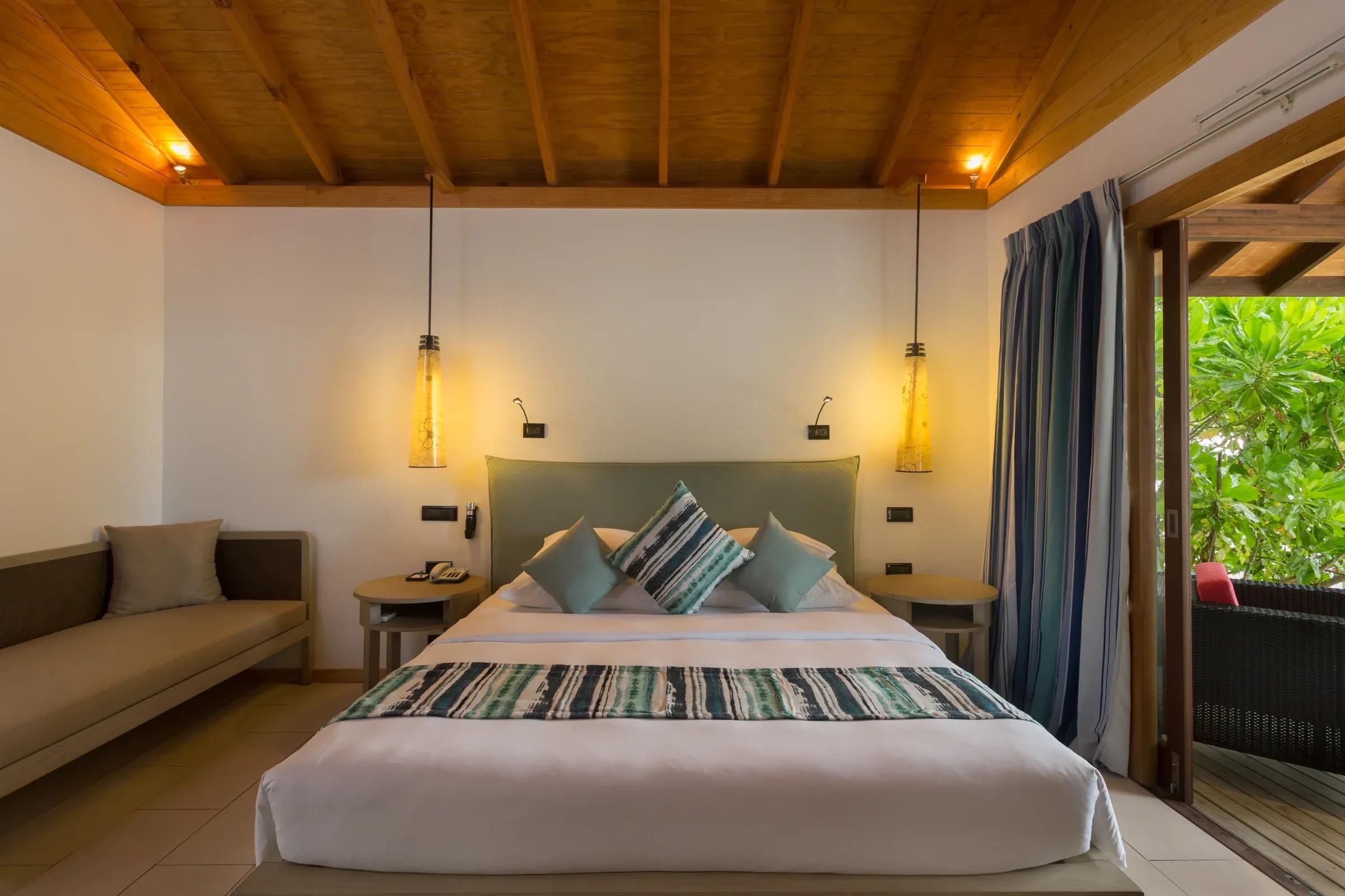 Camera da letto della Adjacent Beachfront Villa con letto matrimoniale e vista sul giardino al Vilamendhoo Maldives.