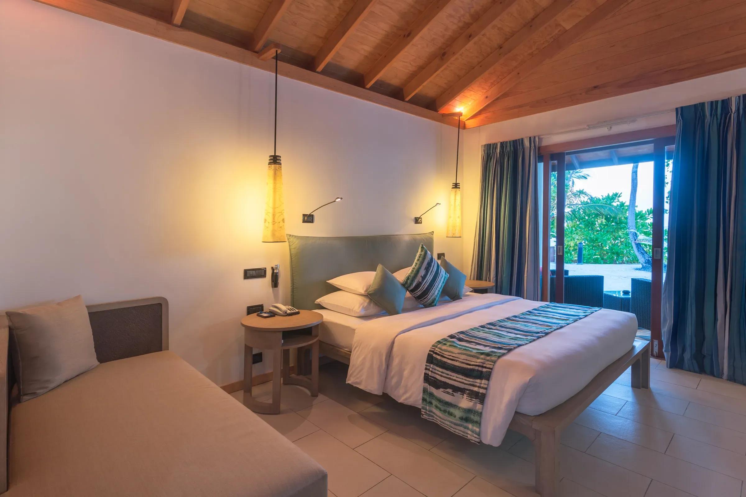 Camera della Adjacent Beachfront Villa con letto matrimoniale e terrazza sulla spiaggia al Vilamendhoo Maldives.