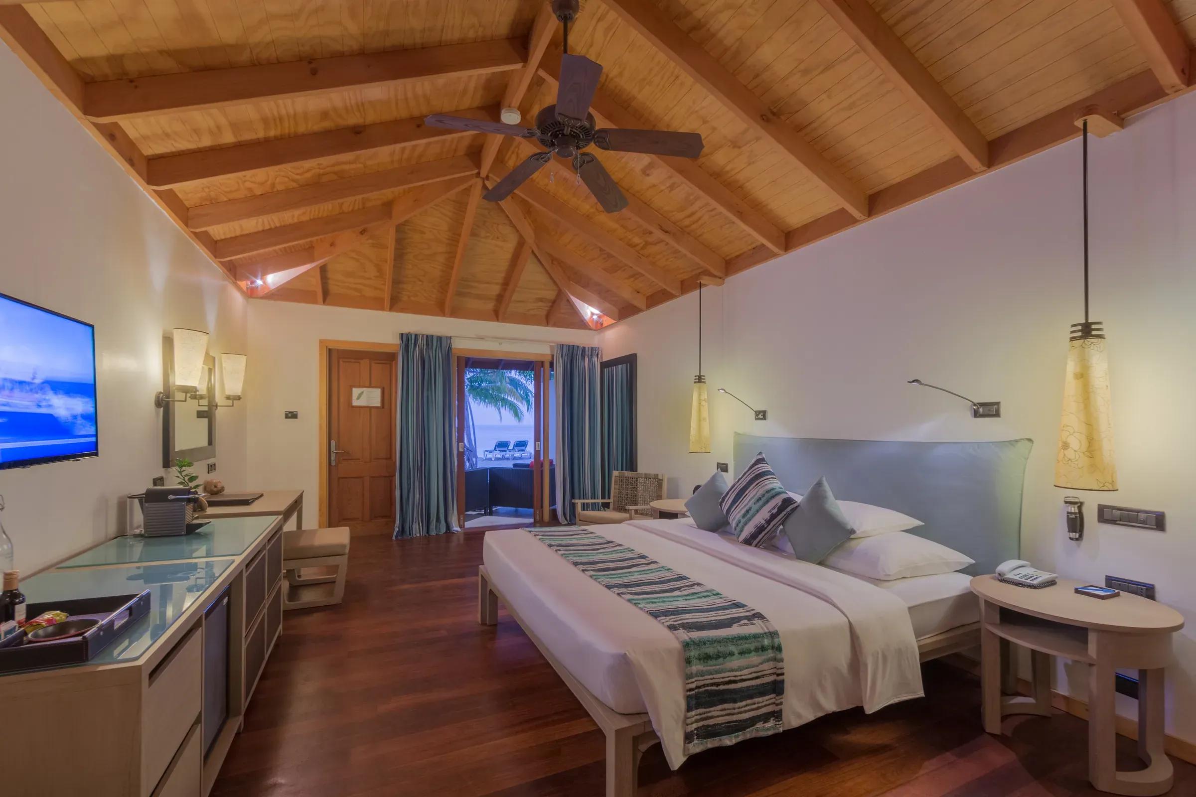 Interno della Romantic Beachfront Villa con letto matrimoniale e accesso alla terrazza del Vilamendhoo Maldives.