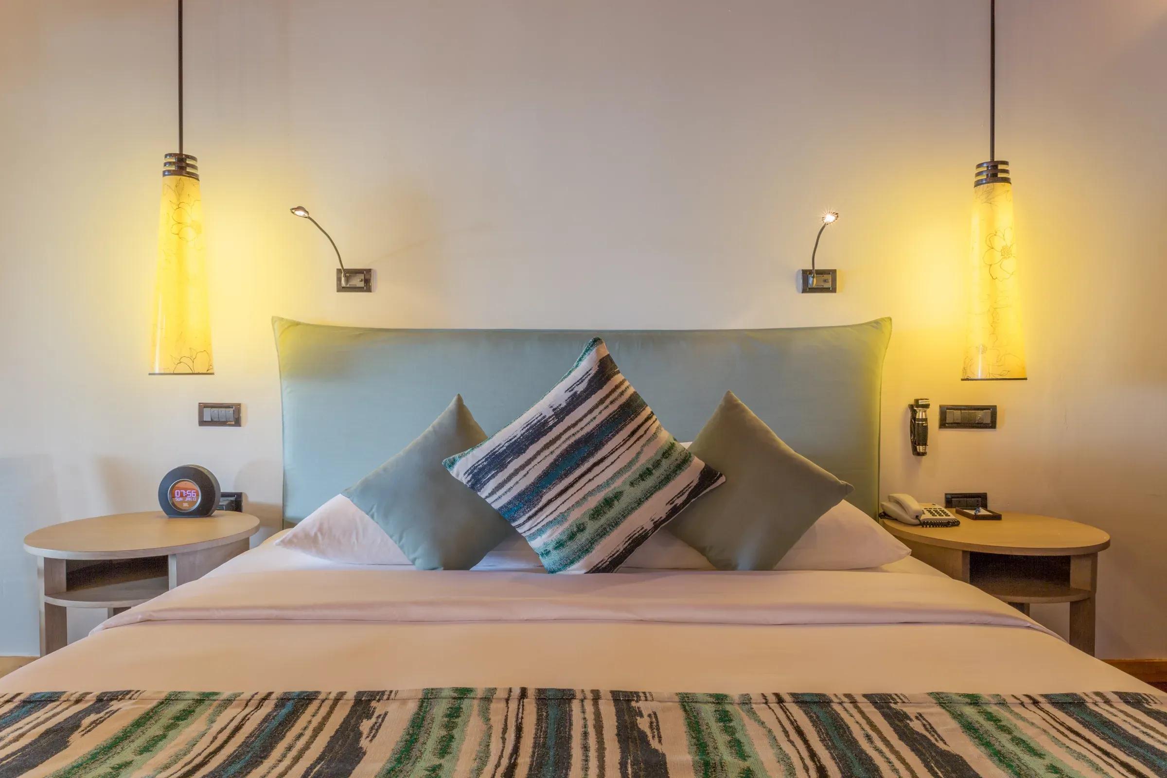 Interno della Romantic Beachfront Villa con letto matrimoniale e lampade a sospensione al Vilamendhoo Maldives.