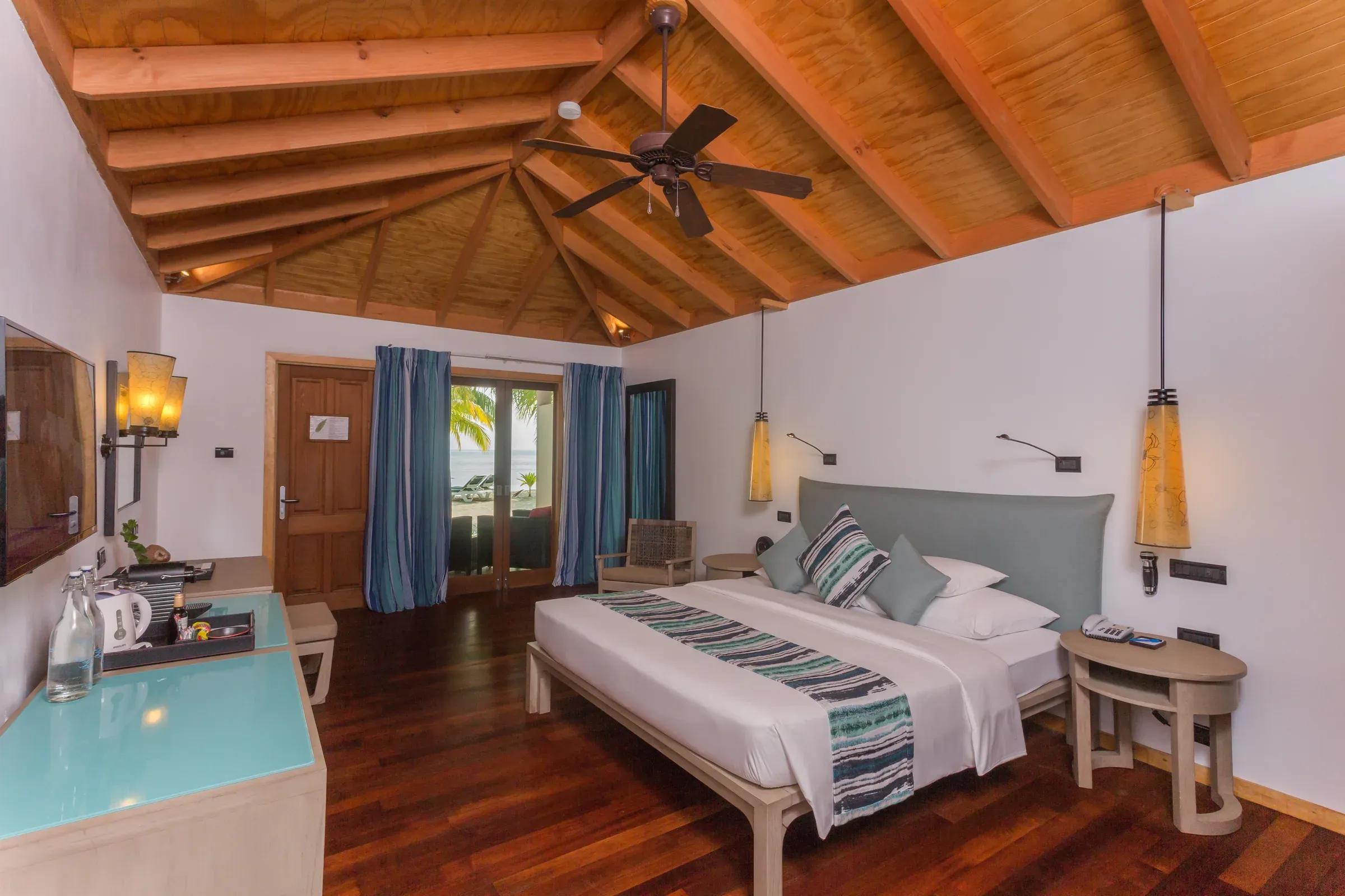 Interno della Romantic Beachfront Villa con letto matrimoniale e accesso alla veranda del Vilamendhoo Maldives.