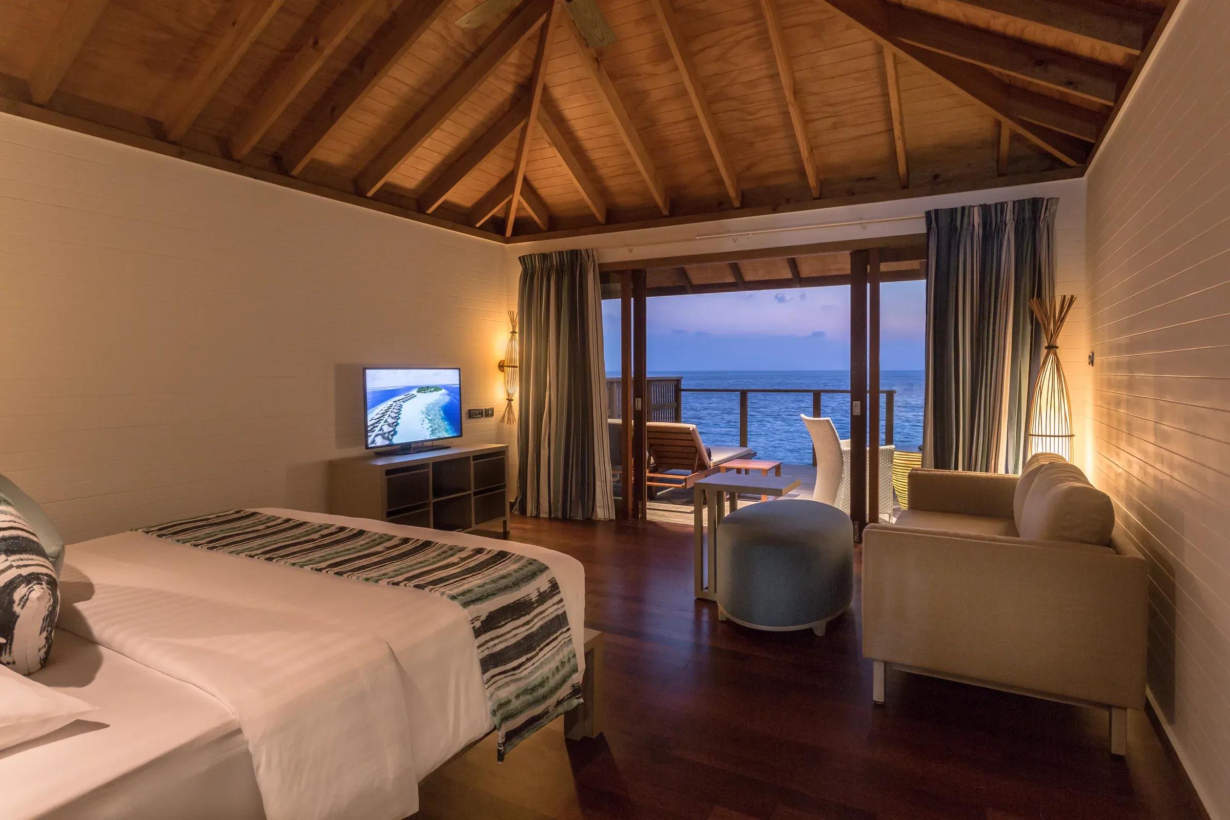 Interno della Romantic Ocean Villa con letto, divano e vista mare al Vilamendhoo Maldives.