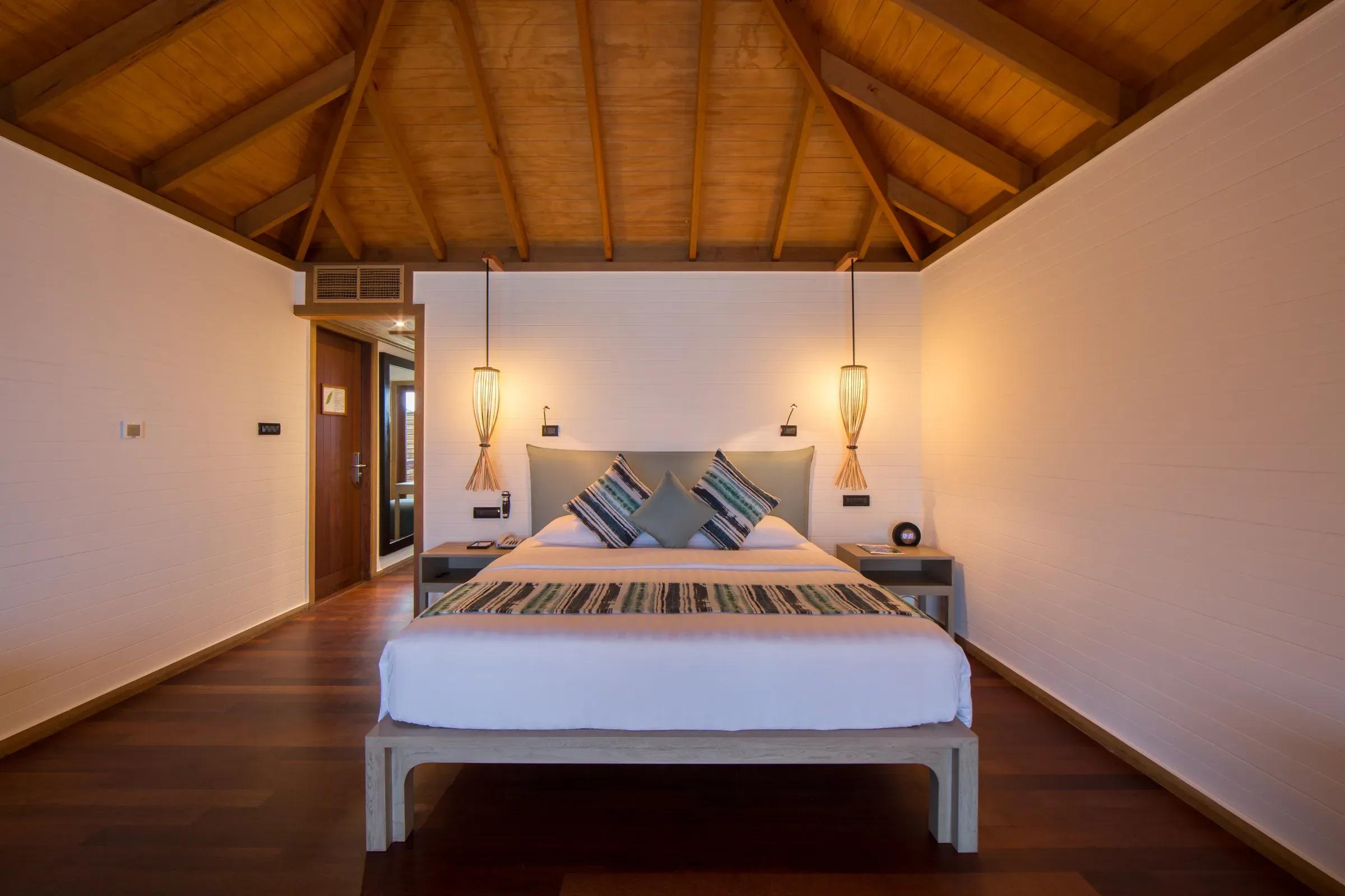 Camera della Romantic Ocean Villa con letto matrimoniale e soffitto in legno al Vilamendhoo Maldives.