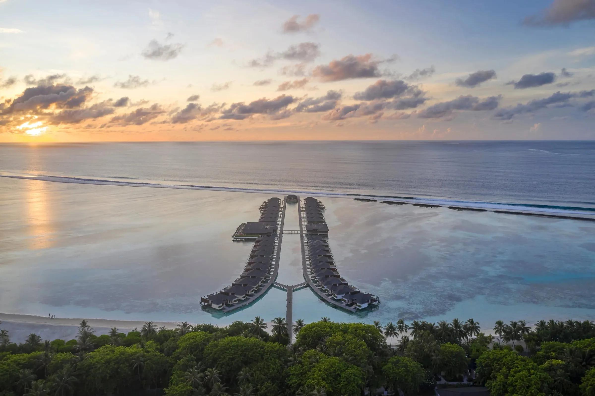 Ville overwater e tramonto sul mare al Villa Nautica, Paradise Island alle Maldive.