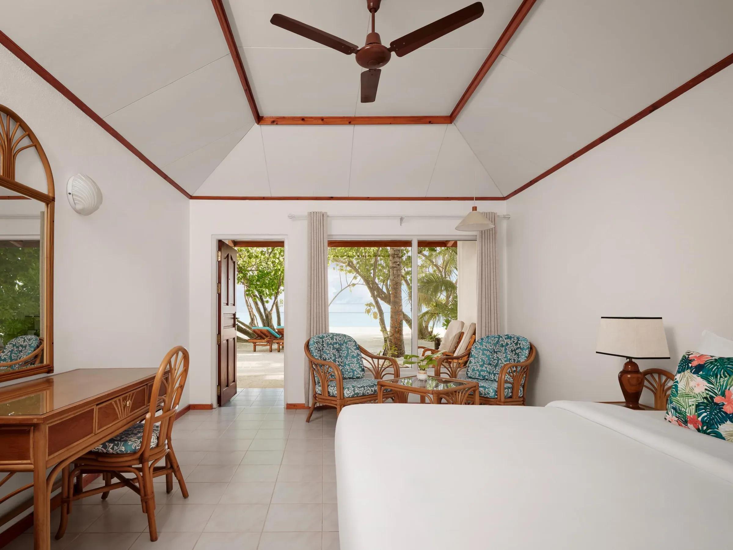 Interni eleganti della Beach Villa al Villa Park Sun Island Resort & Spa, con un letto matrimoniale invitante, arredi in legno di lusso e vista panoramica sulla spiaggia tropicale.