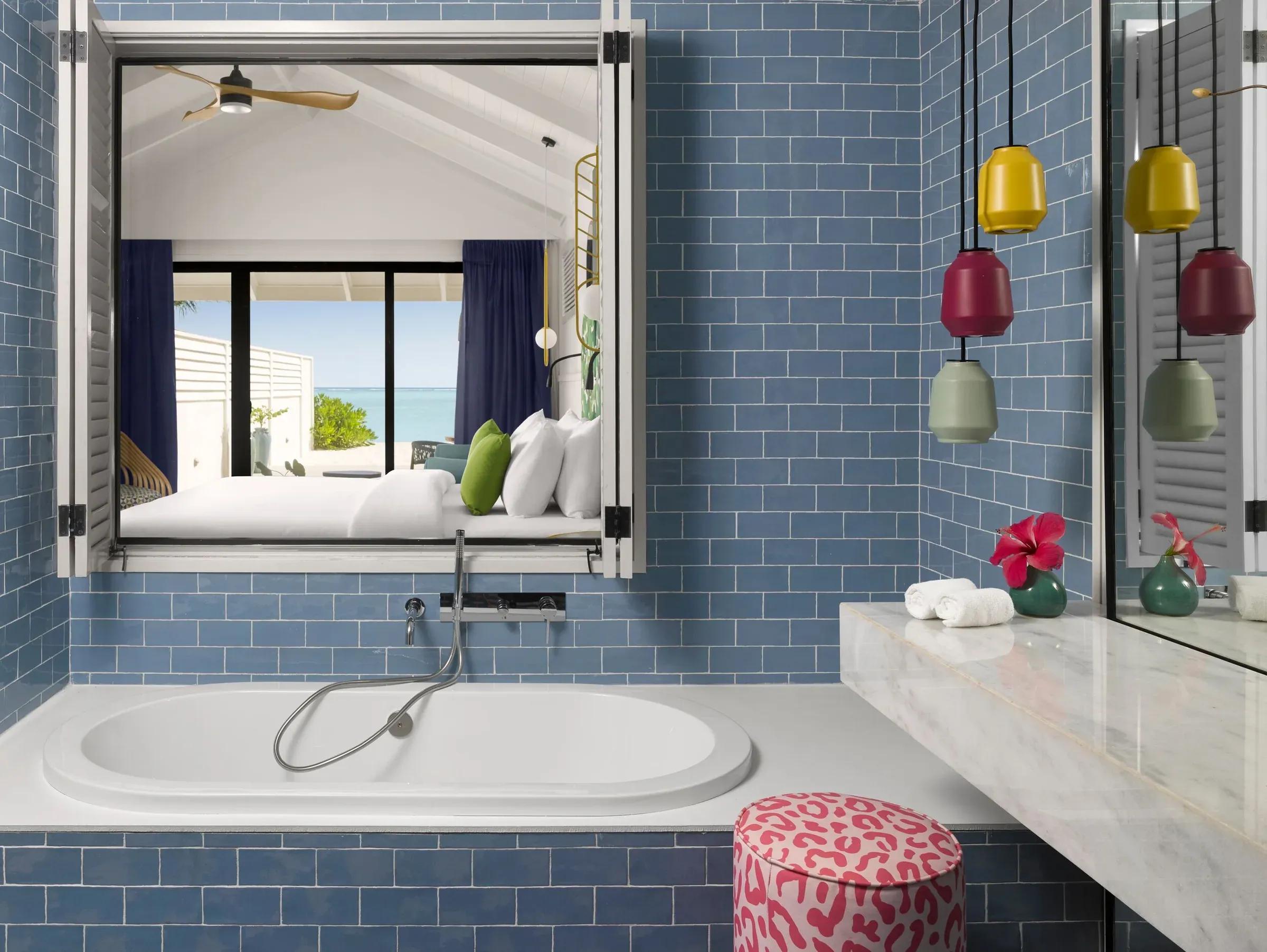 Bagno elegante della Beach Villa with Whirlpool presso il Villa Park Sun Island Resort & Spa con vasca da bagno integrata in ambiente di piastrelle blu, specchio sofisticato e dettagli decorativi colorati, affacciato su una lussuosa camera da letto con letto king size e vista spettacolare sull'oceano.