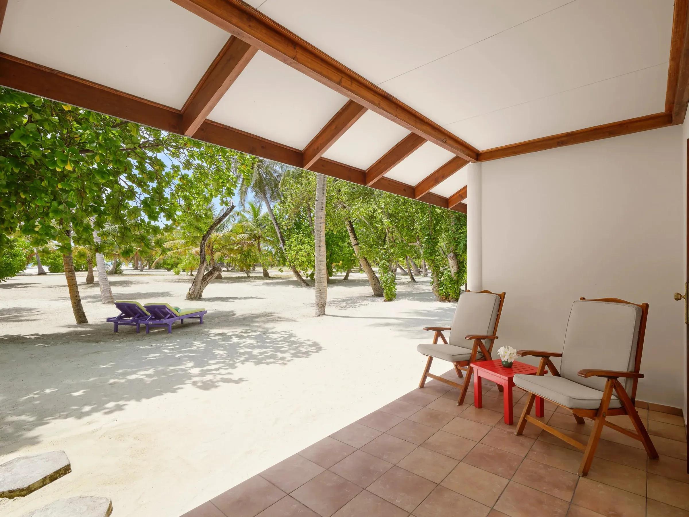 Veranda privata della Island Villa con sedie eleganti, affacciata su una spiaggia di sabbia bianca contornata da palme rigogliose al Villa Park Sun Island Resort & Spa.