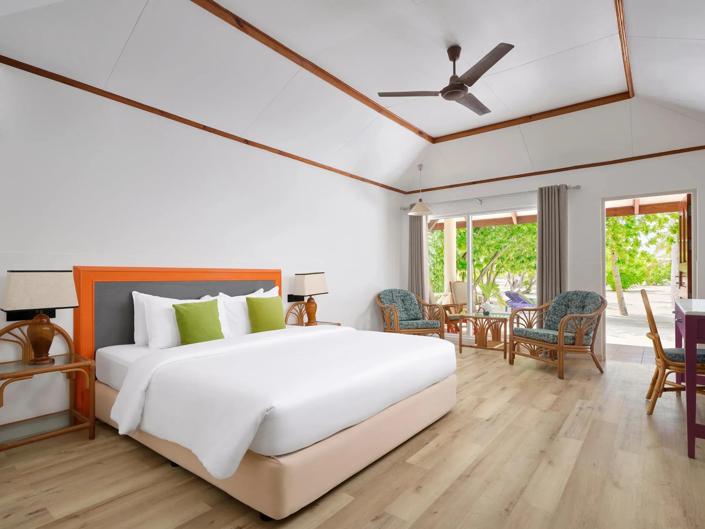 Elegante Island Villa al Villa Park Sun Island Resort & Spa con letto matrimoniale e arredi raffinati, vista sul verde lussureggiante dal patio privato.