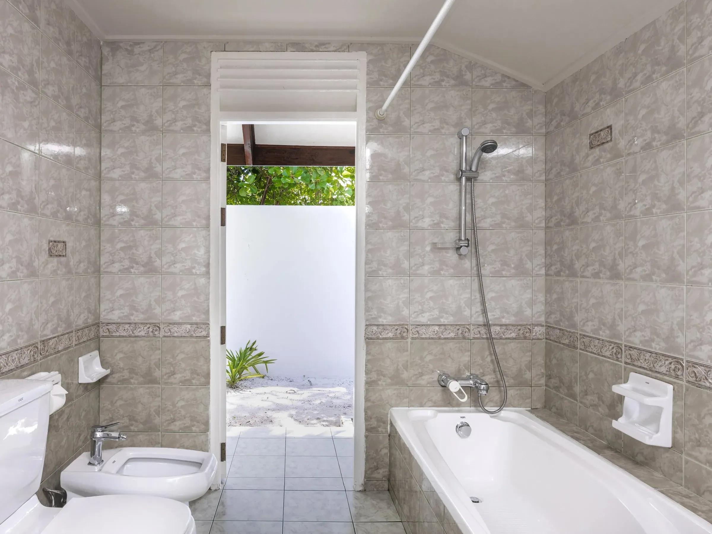 Bagno elegante della Island Villa con vasca e bidet, vista su un giardino tropicale al Villa Park Sun Island Resort & Spa.