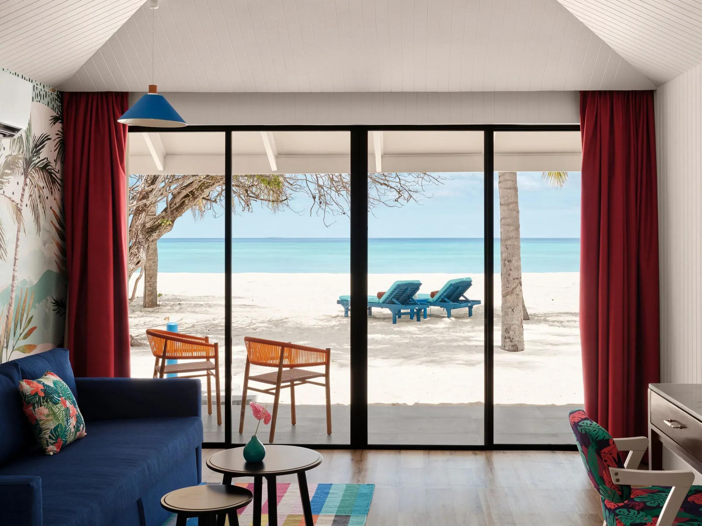 Luminosa zona giorno della Lagoon Beach Villa con arredi di design e ampia vetrata con accesso diretto alla spiaggia di sabbia bianca e vista sulla laguna turchese del Villa Park Sun Island Resort & Spa.