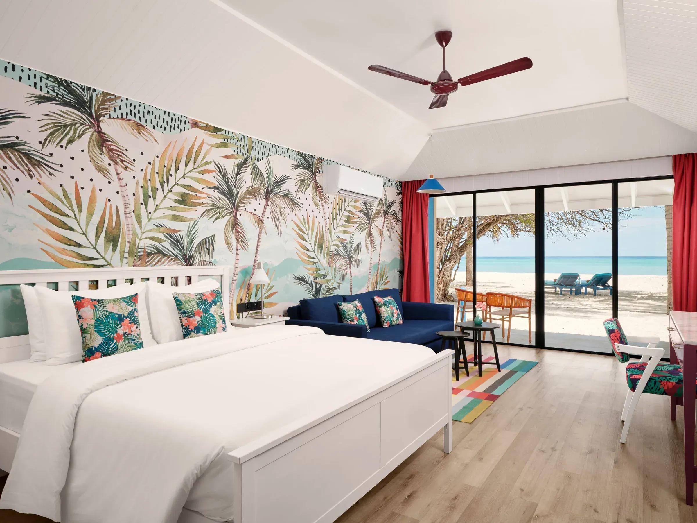 Elegante Lagoon Beach Villa presso il Villa Park Sun Island Resort & Spa, dotata di un ampio letto matrimoniale dalle lenzuola candide, mobili raffinati con tocchi di colore, e un panorama spettacolare della spiaggia privata attraverso ampie vetrate.