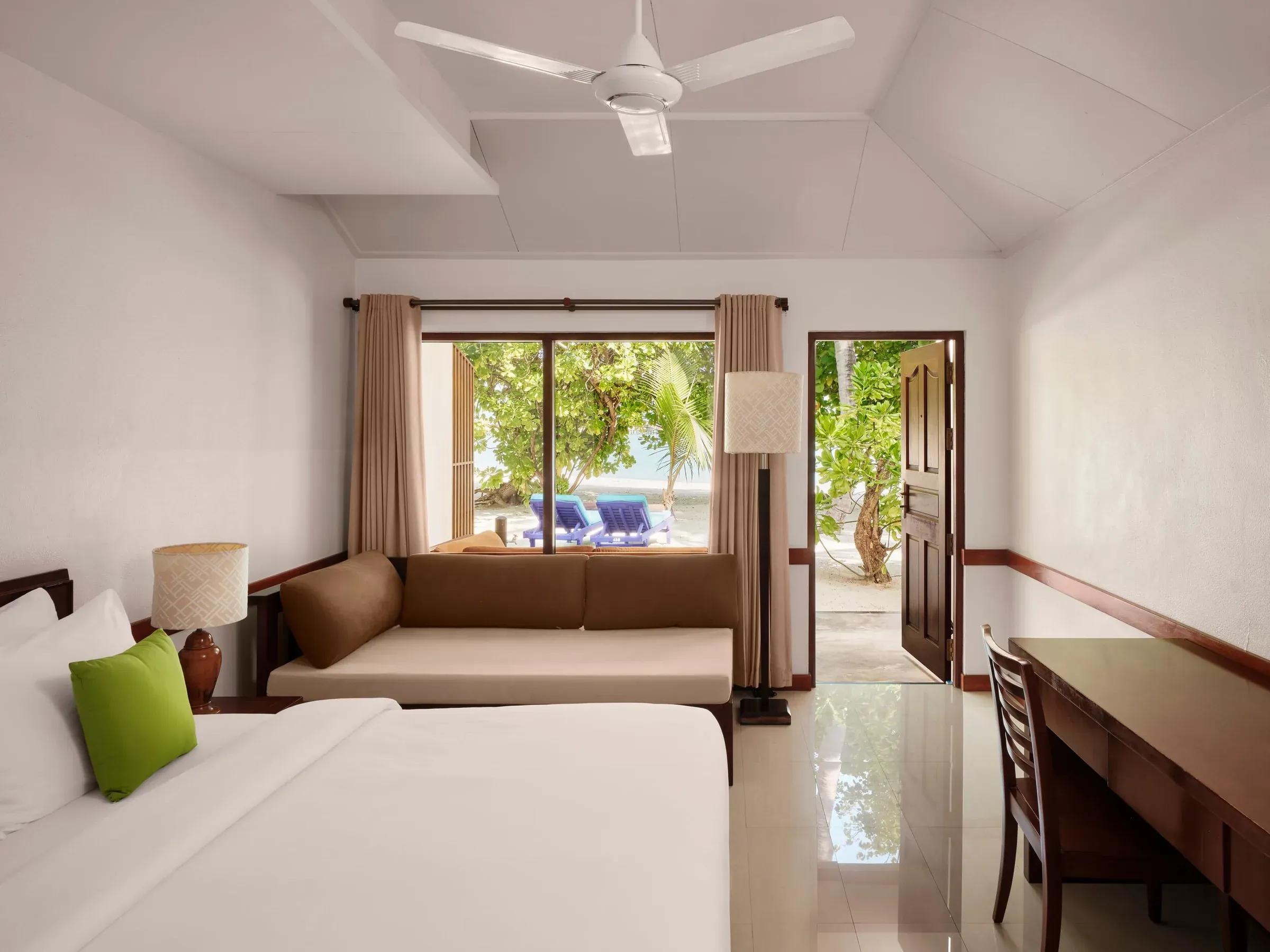 Interno elegante della Sunset Beach Villa al Villa Park Sun Island Resort & Spa, con un ampio letto matrimoniale, decorazioni raffinate, vista su una terrazza privata verso il mare e accesso diretto alla spiaggia.