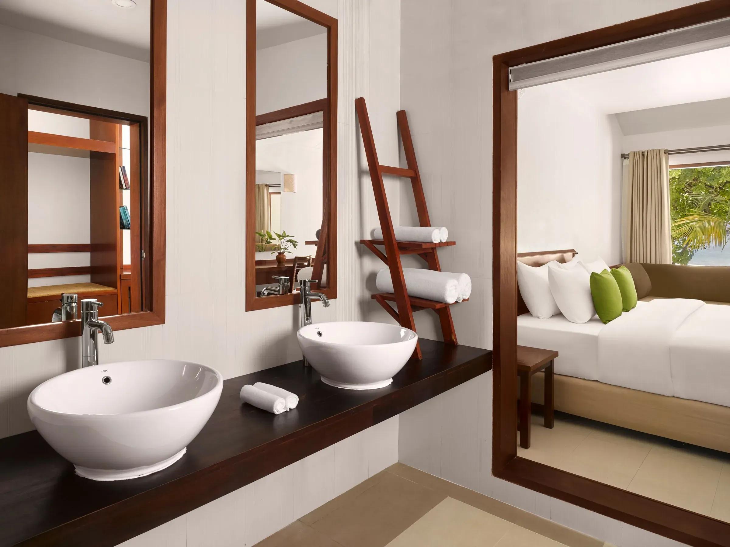 Elegante bagno della Sunset Beach Villa con doppio lavabo, accanto una camera da letto con vista sul giardino tropicale del Villa Park Sun Island Resort & Spa.