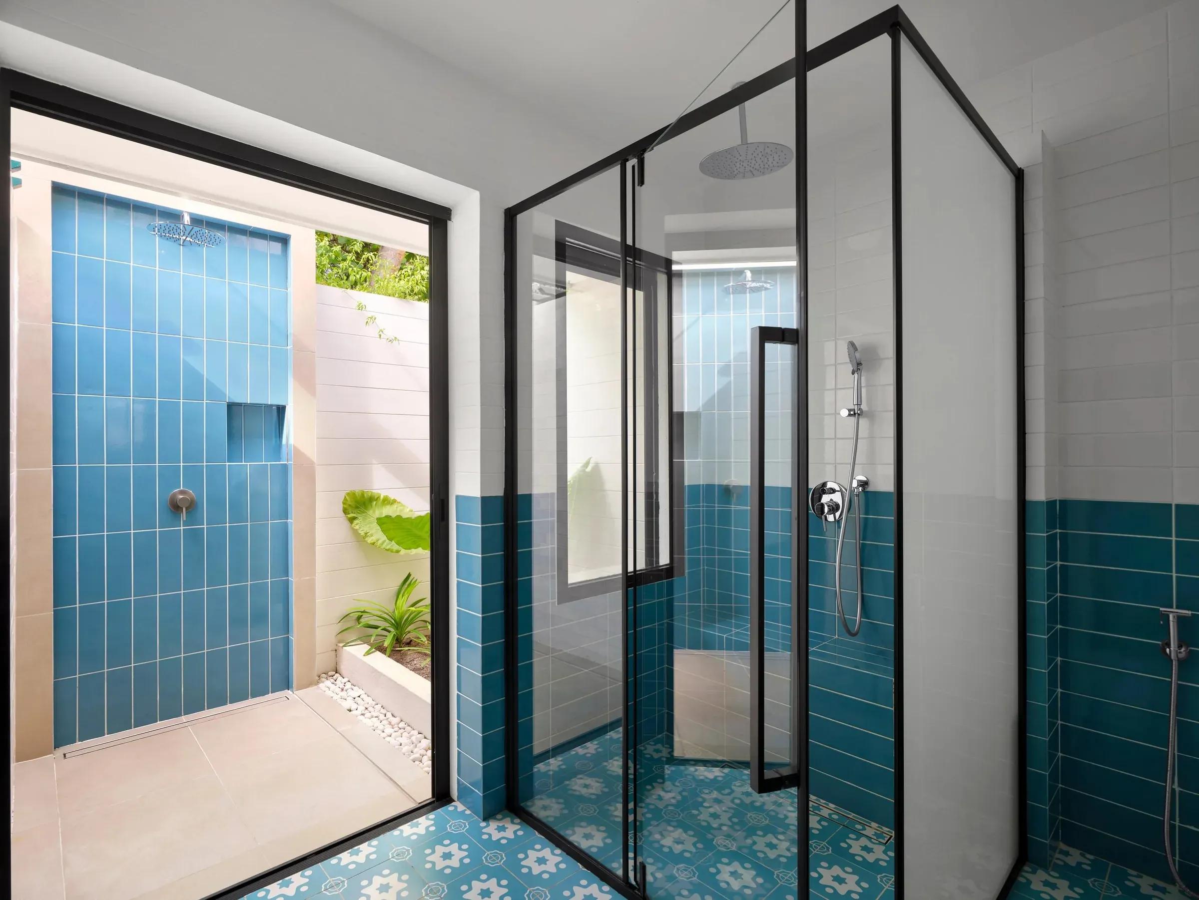 Elegante bagno della Sunset Deluxe Beach Villa con doccia esterna rivestita in piastrelle blu al Villa Park Sun Island Resort & Spa, circondato da piante tropicali.