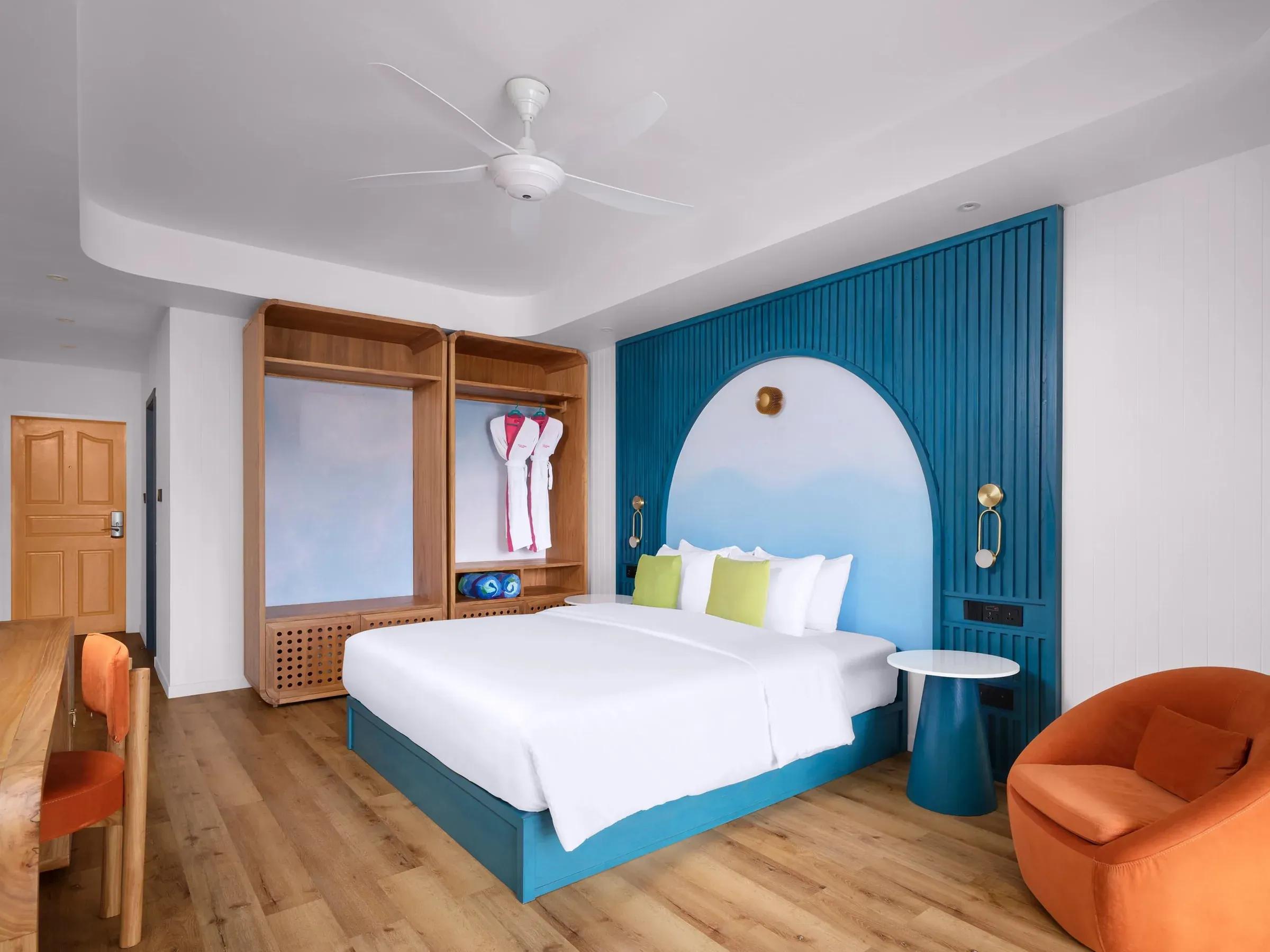 Interno della Sunset Deluxe Beach Villa al Villa Park Sun Island Resort & Spa, con letto confortevole incorniciato da eleganti pannelli blu e arancioni, arredamento moderno e atmosfera rilassante ideale per un soggiorno di lusso.