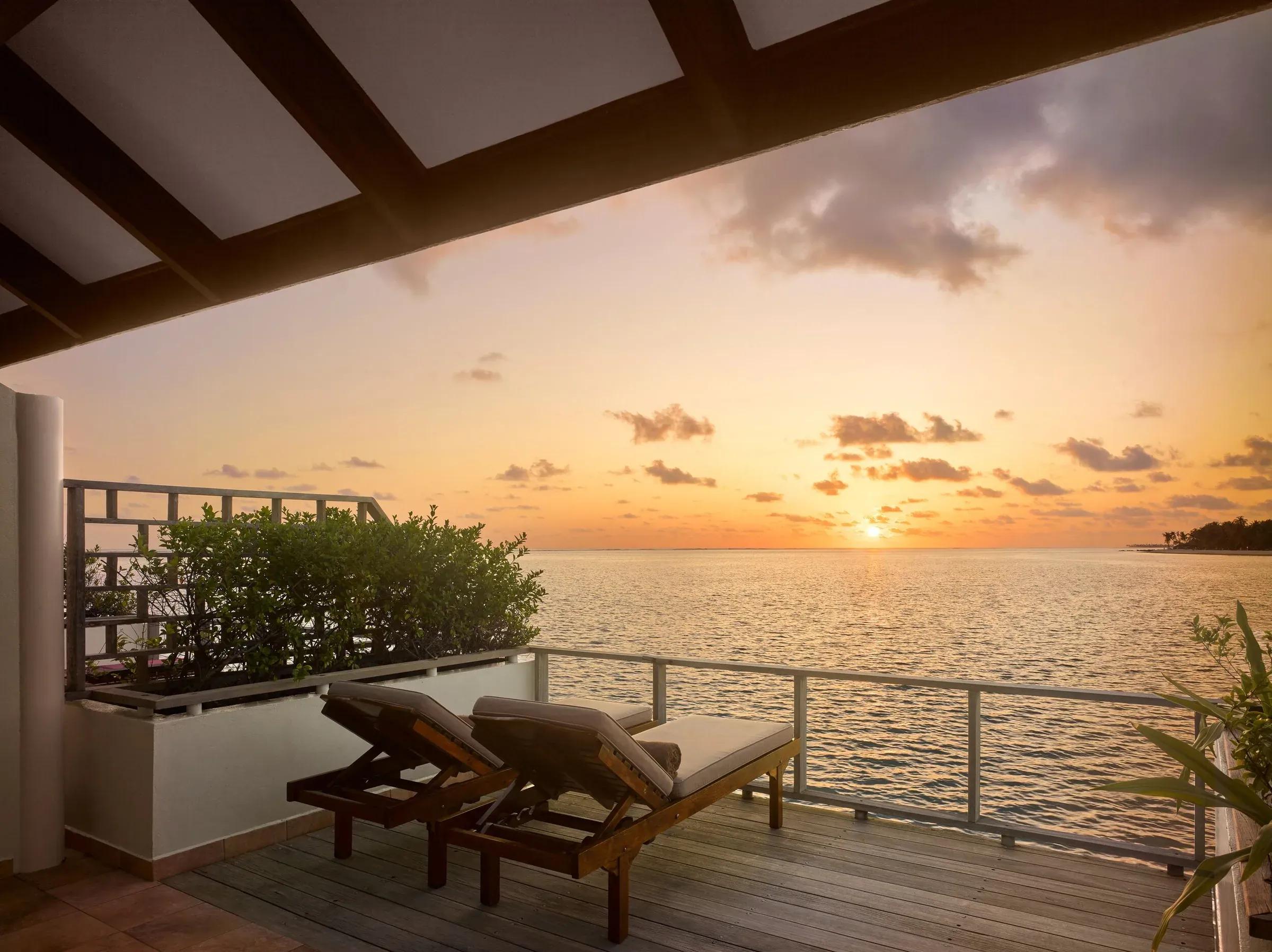Terrazza in legno con lettini e ringhiera della Sunset Water Villa del Villa Park Sun Island Resort & Spa con vista sul tramonto