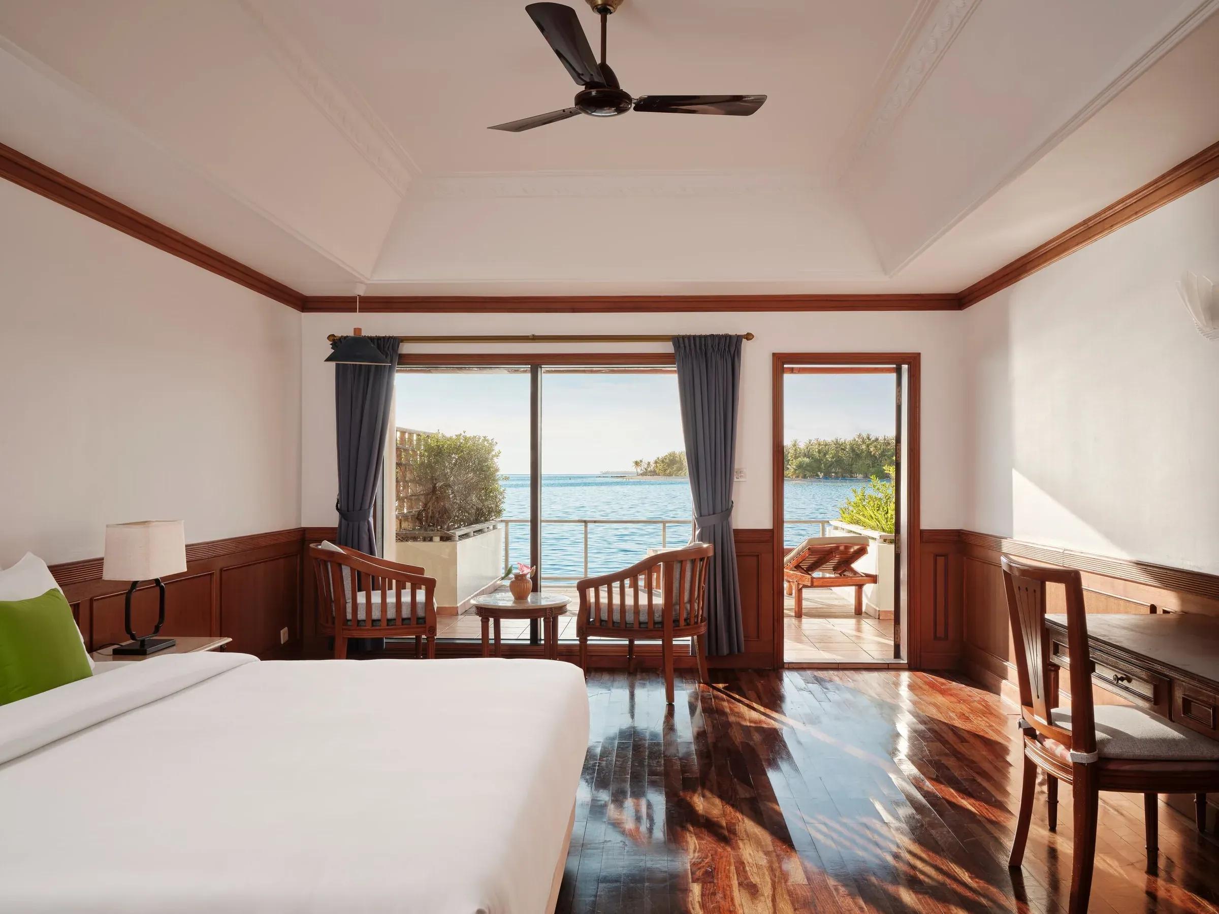 Camera Sunset Water Villa con letto, terrazza vista mare e mobili in legno al Villa Park Sun Island Resort & Spa