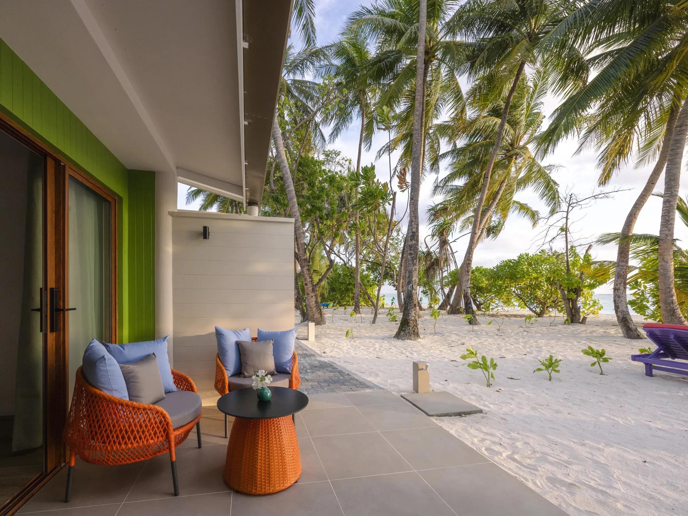 Terrazza della Two Bedroom Family Beach Villa con due poltrone e tavolo, vista palme e spiaggia al Villa Park Sun Island Resort & Spa.