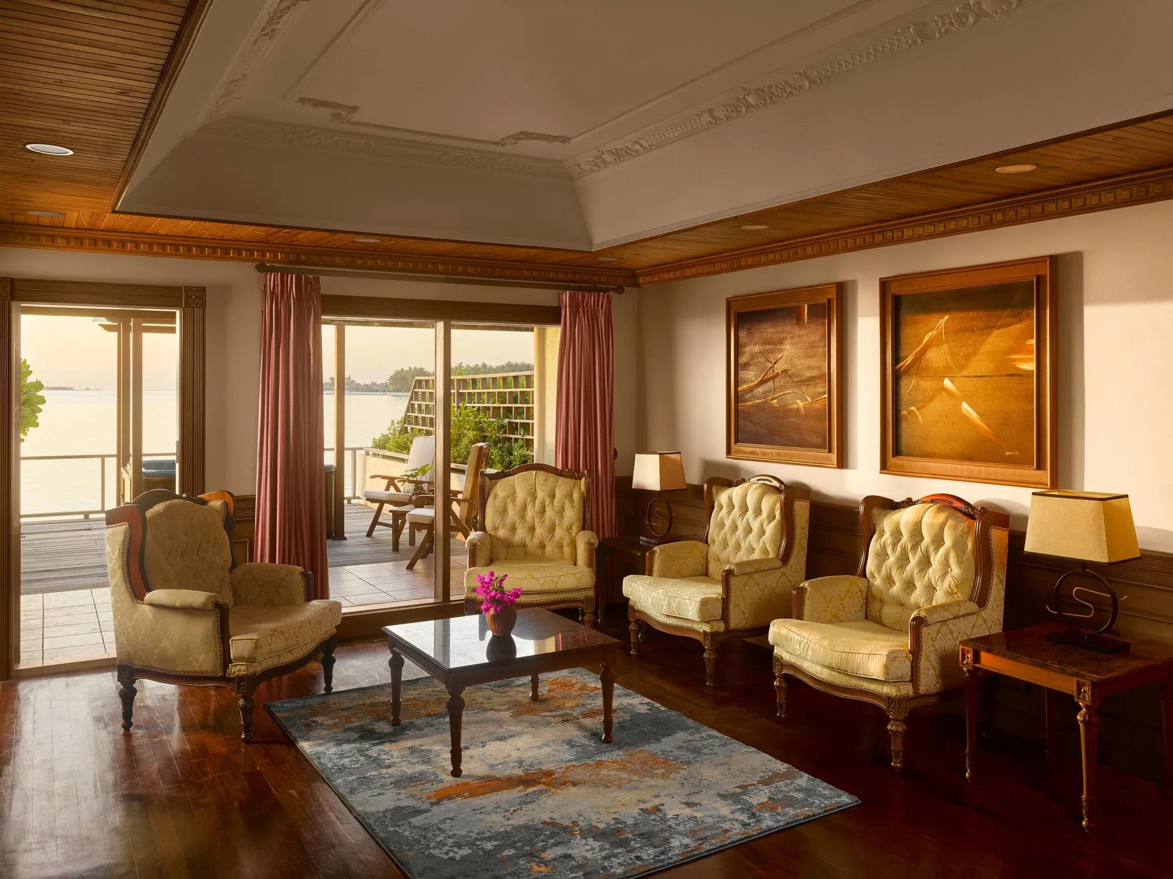 Elegante salotto della Two Bedroom Overwater Suite con arredi classici, pavimento in legno pregiato e accesso alla terrazza privata con vista sull'oceano al Villa Park Sun Island Resort & Spa.