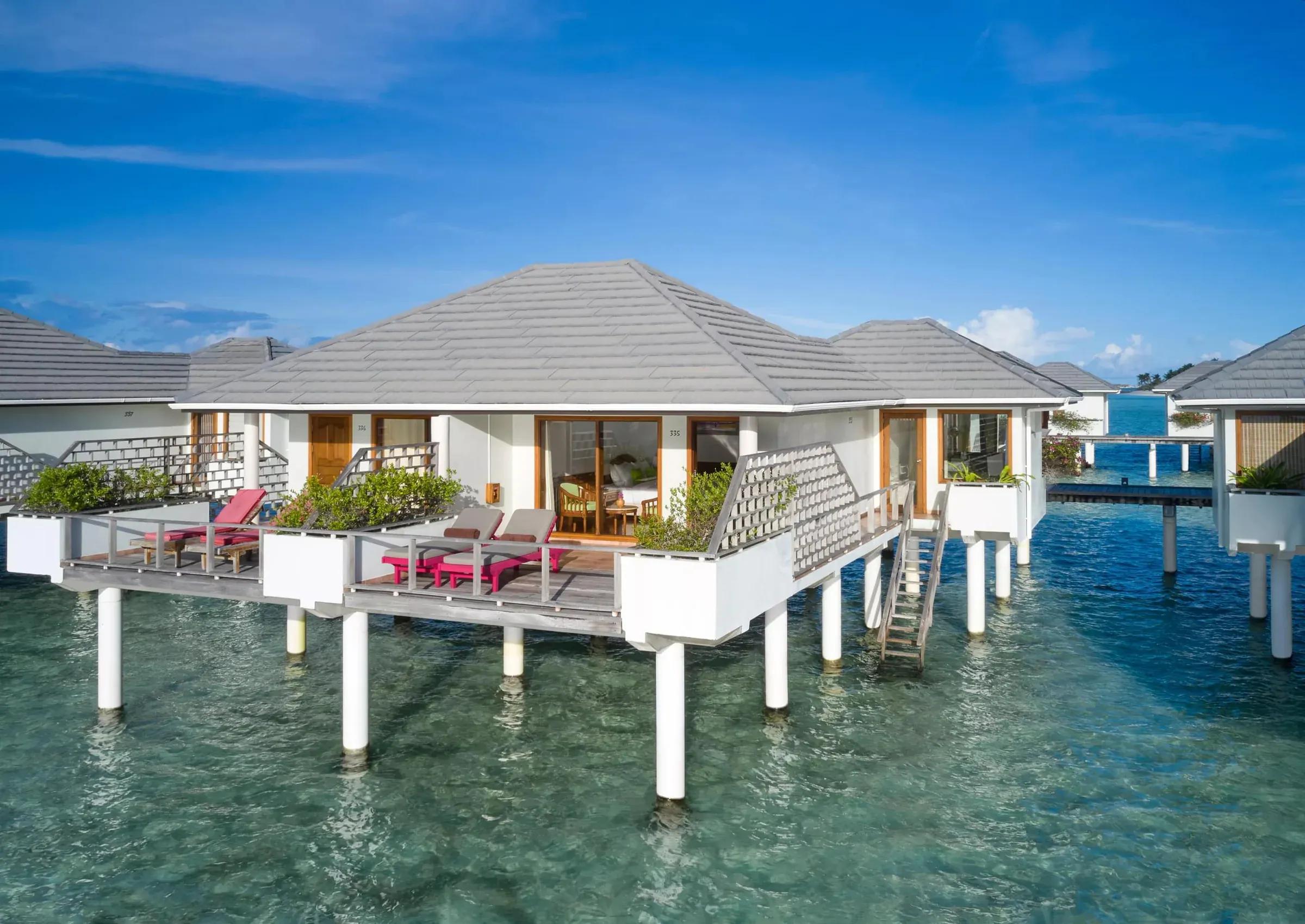 Water Villa con terrazza su palafitte e lettini al Villa Park Sun Island Resort & Spa.