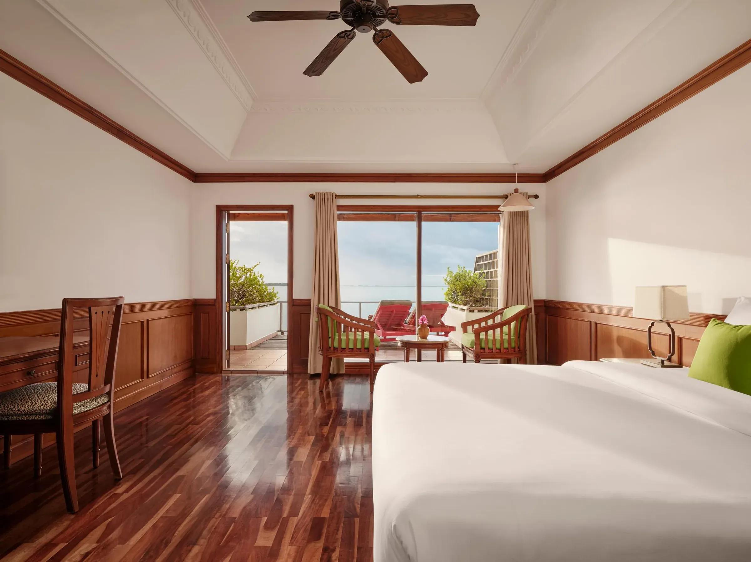 Interno della Water Villa con letto, sedie, terrazza e vista mare al Villa Park Sun Island Resort & Spa.